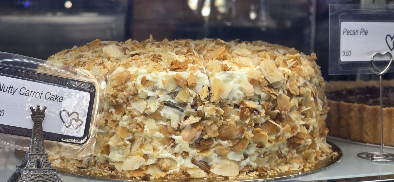 Nutty carrot cake covered in toasted almonds and coconut, beside a pecan pie