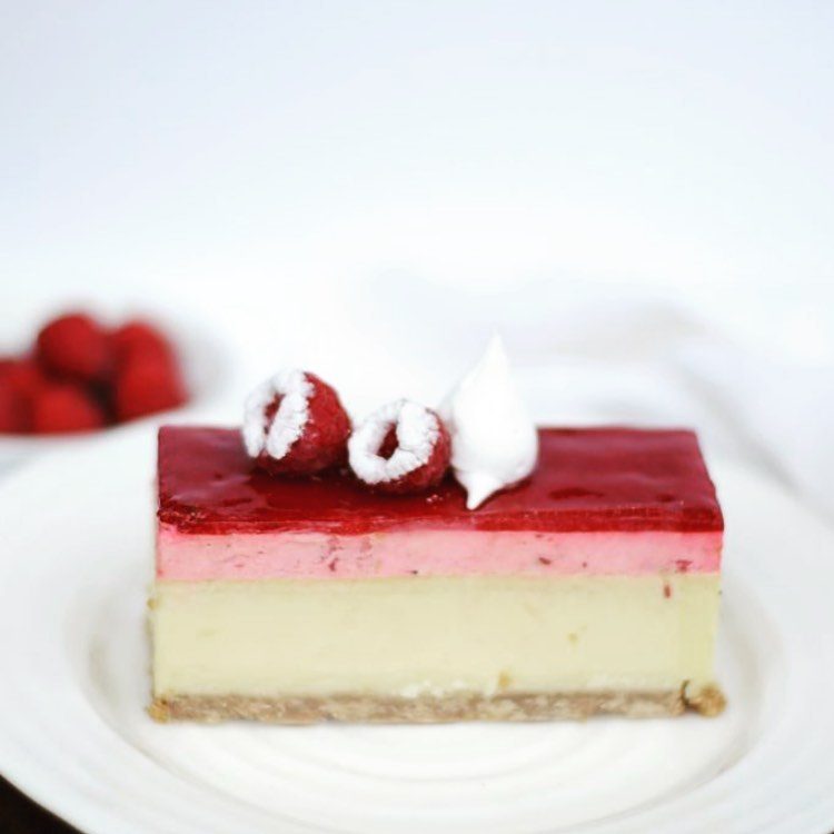 A slice of raspberry baked cheesecake with meringue and fresh raspberries